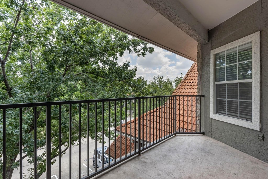 the balcony has a view of the trees and the house